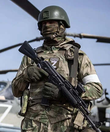 Военнослужащий на фоне вертолёта армейской авиации